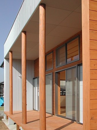木造　熊本K邸1、玄関脇の木テラスと木の列柱と杉板の外壁部分がガルバリウム鋼板に映えます