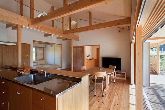 木造　熊本S邸4、キッチン側からリビングダイニングの先の玄関や和室まで視線が開けます、勾配天井で高さを確保しつつ木の構造部分も魅せています