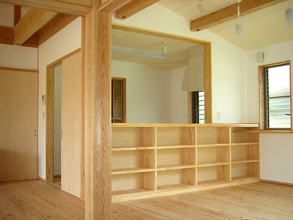 木造　熊本T邸4、和室からキッチンを見たところで、傾斜のついた天井や太めの柱と収納棚つきカウンターが見えます