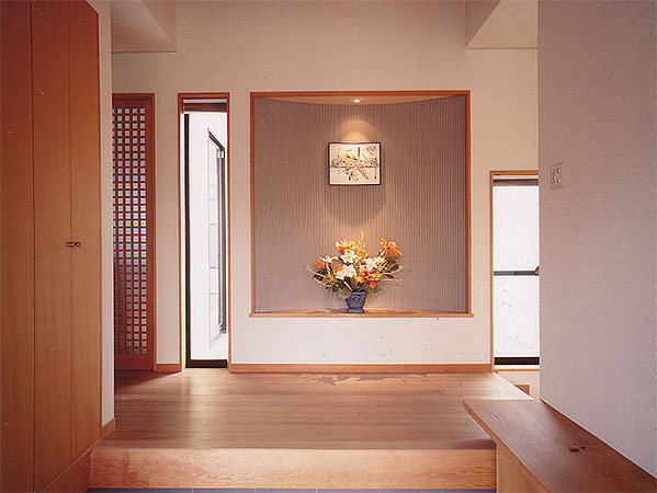 木造　熊本W邸3、玄関正面にある曲面壁の飾り棚、その両サイドの窓は中庭に面していて、右手に数段下がる階段が少し見えます