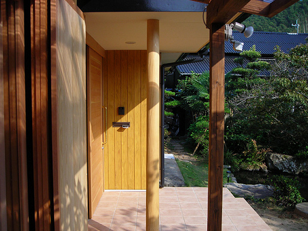 木造　熊本N邸4、玄関脇の外壁は木板貼り、丸柱が玄関庇を支えます