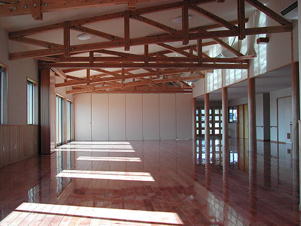 木造　松橋デイサービスセンター3、療養室からデイルームや訓練室まで空間が続き移動間仕切りで区切ることも可能、この大空間は木製トラスで支えて天井下に現しで魅せています